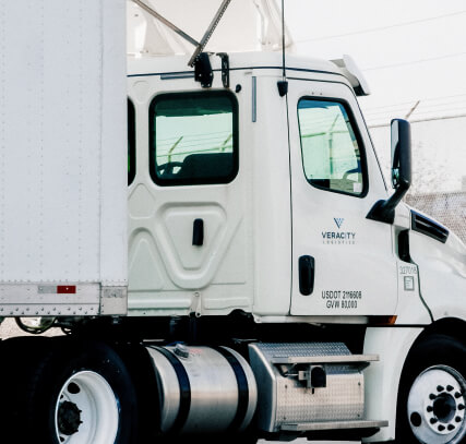 The side of a white tractor trailer with the Veracity logo on the door.